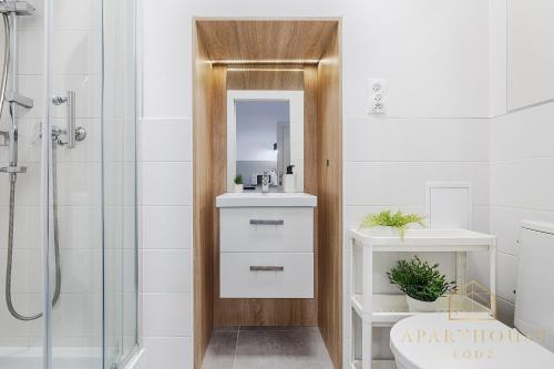 uma casa de banho com um chuveiro, um lavatório e um espelho. em Royal Style Apartment em Lódź