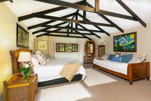 een slaapkamer met 2 bedden en een balkenplafond bij La Bastide Guest House in Hartbeespoort