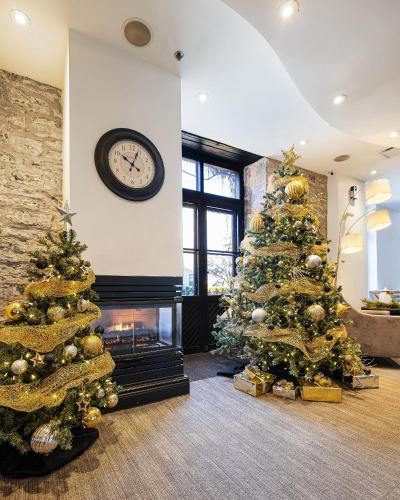 two christmas trees in a living room with a fireplace at Hotel Port-Royal in Quebec City