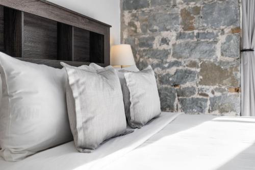 a bed with white pillows and a brick wall at Hotel Port-Royal in Quebec City