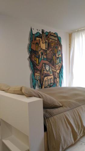 une chambre avec un mur orné d'une peinture de maisons dans l'établissement Lons appartement T1 centre ville, à Lons-le-Saunier