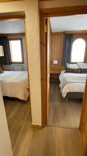 a small room with two beds and two windows at Meribel Centre La Chaudanne, real ski in and out, 3 bedrooms 2 bathrooms newly renovated, Chalet l'Épervière in Méribel