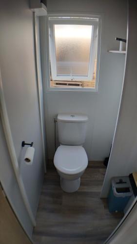 a small bathroom with a toilet with a window at MOBIL HOME Tout confort - Côte Landaise in Saint-Julien-en-Born
