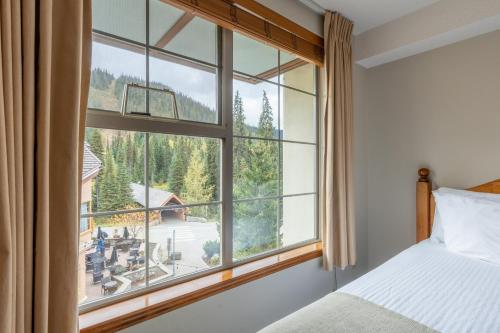 a bedroom with a large window with a mountain view at Sundance Lodge in Sun Peaks