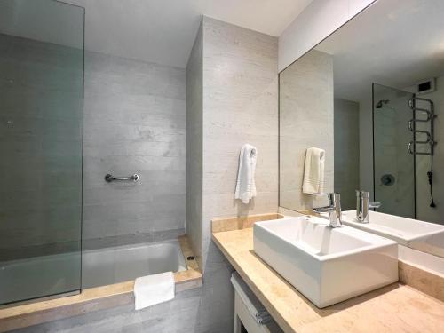 y baño con lavabo, ducha y bañera. en Emerald Apartments - Parrillero exclusivo, en Punta del Este