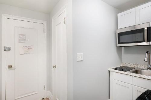 eine weiße Küche mit einer Spüle und einer Mikrowelle in der Unterkunft 73-201 New 1BR 1Bth UWS Doorman Gym in New York
