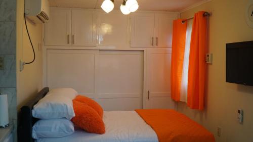 ein Schlafzimmer mit einem Bett mit einer orangefarbenen Decke in der Unterkunft Tranquility Place in Willemstad