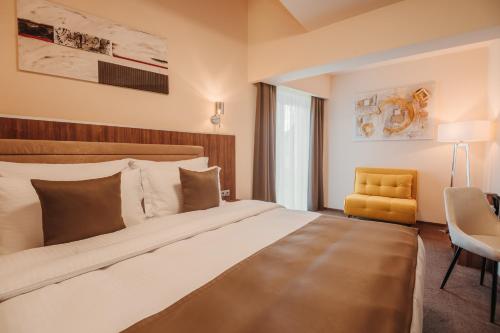 a bedroom with a large bed and a yellow chair at PENSIUNEA GAMBRINUS **** in Miercurea-Ciuc