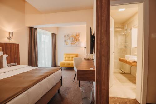 una camera d'albergo con letto, scrivania e bagno di PENSIUNEA GAMBRINUS **** a Miercurea-Ciuc