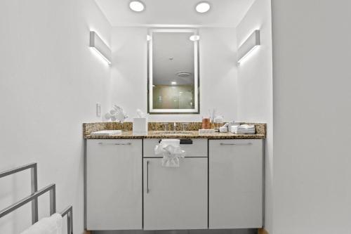 a white bathroom with a sink and a mirror at Luxury Condo Hotel with full kitchen, located at 5 mints walk to the beach in Fort Lauderdale