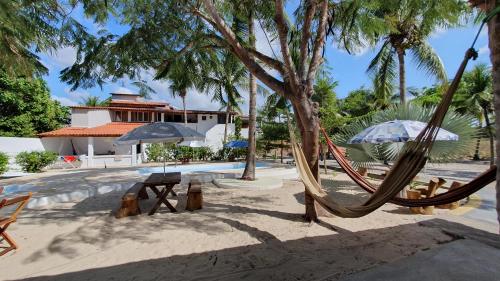 a resort with hammocks and umbrellas in the sand at Pousada Unidos in Jijoca de Jericoacoara