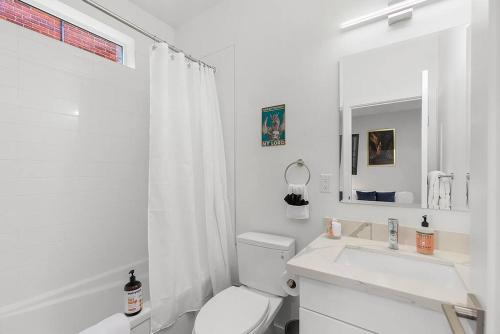 a white bathroom with a toilet and a sink at Meleys' Crimson Keep: Driftmark's Suite in Seattle