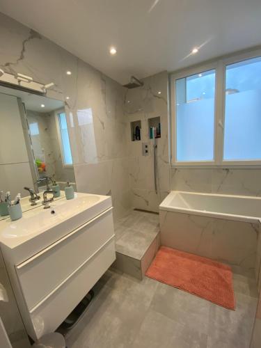 a white bathroom with a tub and a sink at Appartement cosy, situé à 5 mins de Roland Garros et du Parc des princes in Boulogne-Billancourt