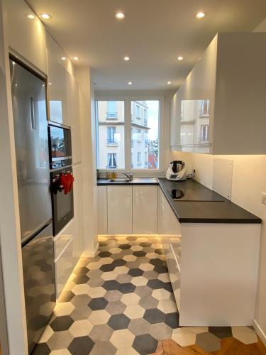 uma cozinha com armários brancos e um piso xadrez em Appartement cosy, situé à 5 mins de Roland Garros et du Parc des princes em Boulogne-Billancourt