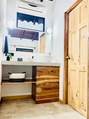 a bathroom with a sink and a wooden door at Calipso Ocean Lodge- Avellana Beach Hotel in Playa Avellana