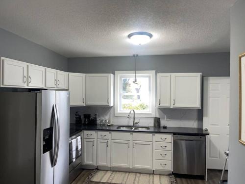 a kitchen with white cabinets and a stainless steel refrigerator at Miracle House in Anoka
