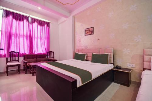 a bedroom with a bed and chairs and pink curtains at Tiger View Hotel in Sawāi Mādhopur