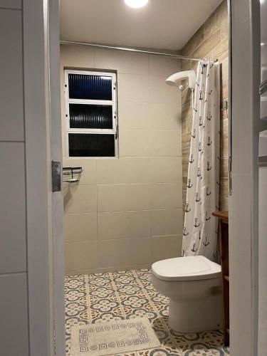 a bathroom with a toilet and a shower curtain at São Francisco do Sul, SC, Praia do Forte. in São Francisco do Sul