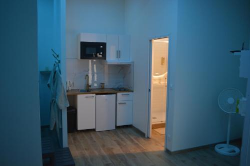 une cuisine avec des armoires blanches et un mur bleu dans l'établissement Eaux Spa, à Rouen