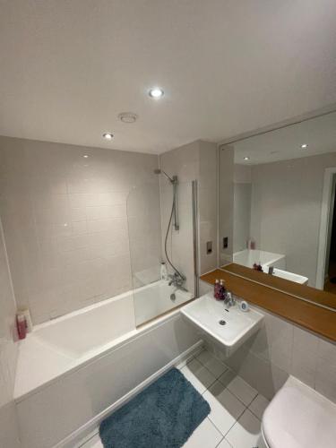 a bathroom with a tub and a sink and a toilet at Manchester Old Trafford CityView En-Suite Apt in Manchester