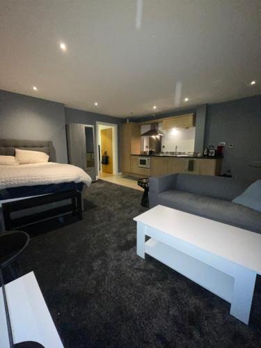 a bedroom with a bed and a couch and a kitchen at Manchester Old Trafford CityView En-Suite Apt in Manchester