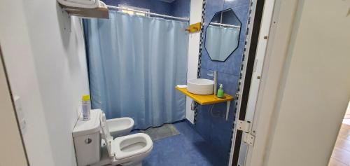 a blue bathroom with a toilet and a mirror at La Bicicleta in Aldea Camarero