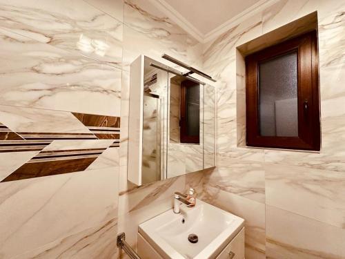 Un baño blanco con lavabo y espejo. en Kathy's Elegance, en Buşteni