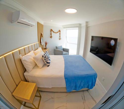 a bedroom with a large bed and a television at Flat Radisson Recife in Recife