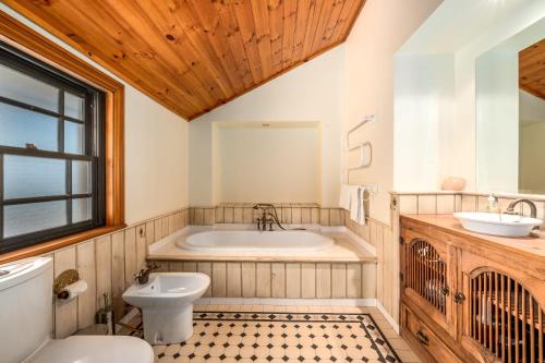 a bathroom with a tub and a toilet and a sink at Bonvilla Estate in Pokolbin