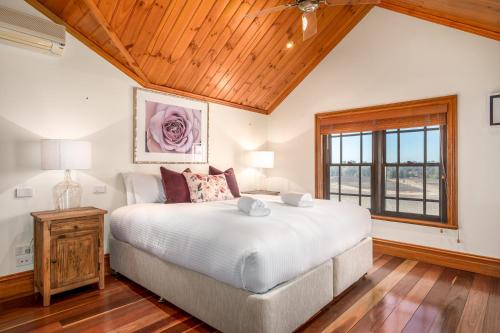 sypialnia z dużym łóżkiem i drewnianym sufitem w obiekcie Bonvilla Estate w mieście Pokolbin