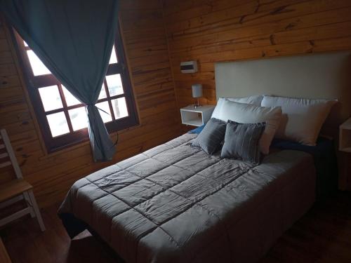 a bedroom with a large bed with two windows at Cabañas Las Escondidas in Chascomús