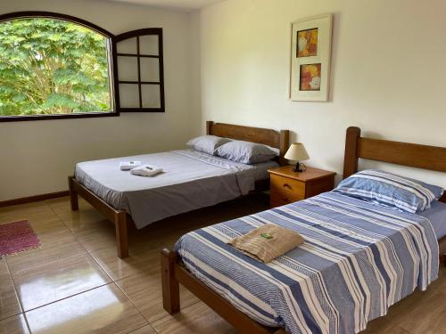 um quarto com 2 camas e uma janela em Recanto da Paz, Miguel Pereira RJ em Miguel Pereira