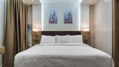 a bedroom with a large bed with two paintings on the wall at Sunflower Residence Victoria Island in Lagos