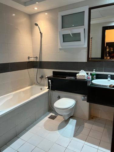 a bathroom with a toilet and a sink and a bath tub at Sky Inn Hostel For Males in Dubai