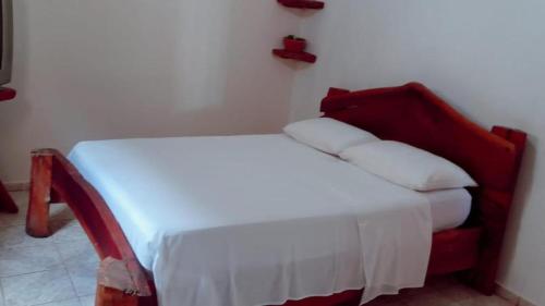 a small bed in a room with a red headboard at Pousada JK in Pirenópolis