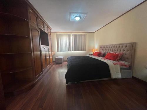 a bedroom with a bed with red pillows on it at CASA NUEVA, CON DECORACIONES Y ACABADOS NUEVOS SOLO PARA FAMILIAS. in Cuenca