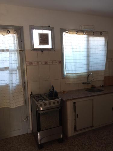 une cuisine avec une cuisinière et un évier et deux fenêtres dans l'établissement Lo de mirella, à La Paloma