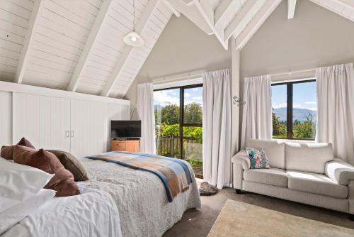 Mountain View Lodge في كوينزتاون: غرفة نوم بسرير واريكة ونوافذ