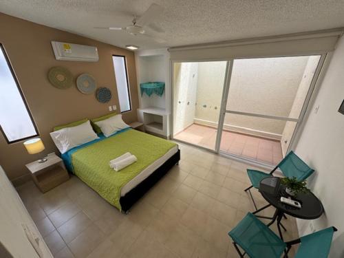 1 dormitorio con cama verde y balcón en Hotel TACALOA INN EXPERIENCE, en Ricaurte