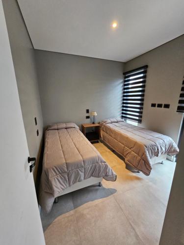 una camera con due letti, un tavolo e una finestra di Andino House a Ushuaia