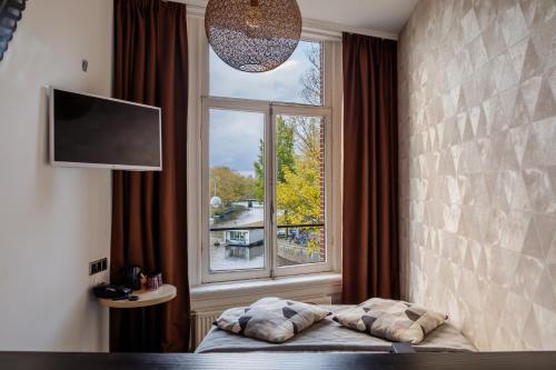 a bed in a room with a large window at Boutique Hotel View in Amsterdam