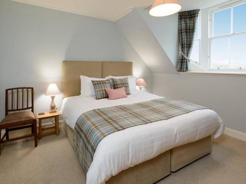 a bedroom with a bed and a chair and a window at Broomrigg Farmhouse in Pencaitland