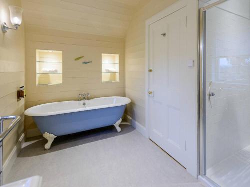 a bathroom with a blue tub and a shower at Broomrigg Farmhouse in Pencaitland