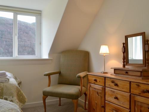 1 dormitorio con silla, espejo y tocador en Glenmeanich Cottage - Uk33789, en Bridgend