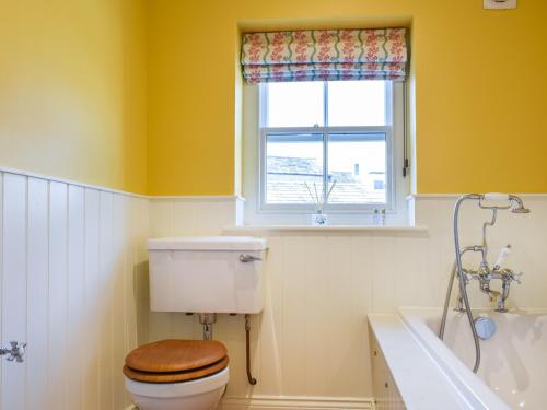 a bathroom with a toilet and a window and a tub at 1 The Reading Room Cottages - Uk37359 in Barningham