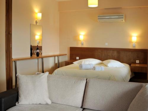 ナフプリオにあるKarayiannis Villasのベッド2台とソファが備わるホテルルームです。
