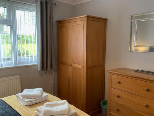 a bedroom with a wooden cabinet and a bed with towels at Rosemary Cottage-uk42032 in Highampton