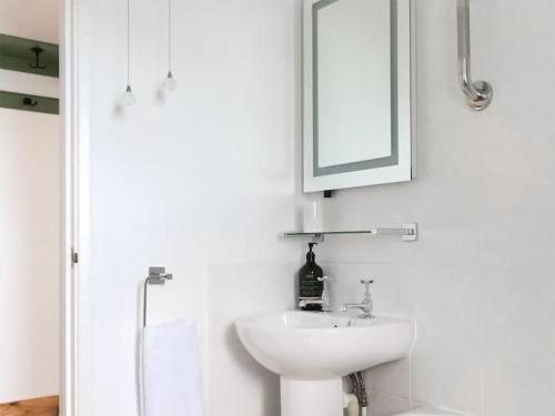 a white bathroom with a sink and a mirror at The Hideaway in Kilve