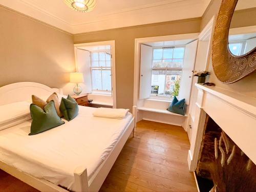 1 dormitorio con cama con almohadas verdes y chimenea en Neuk Hoose, en Crail