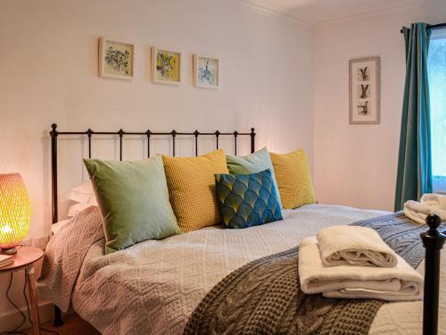 um quarto com uma cama com almofadas coloridas em Newton Cottage em Leitholm